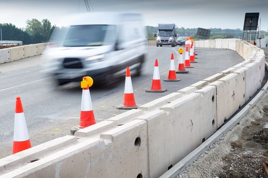Multibloc concrete barriers installed along road works with vans driving past